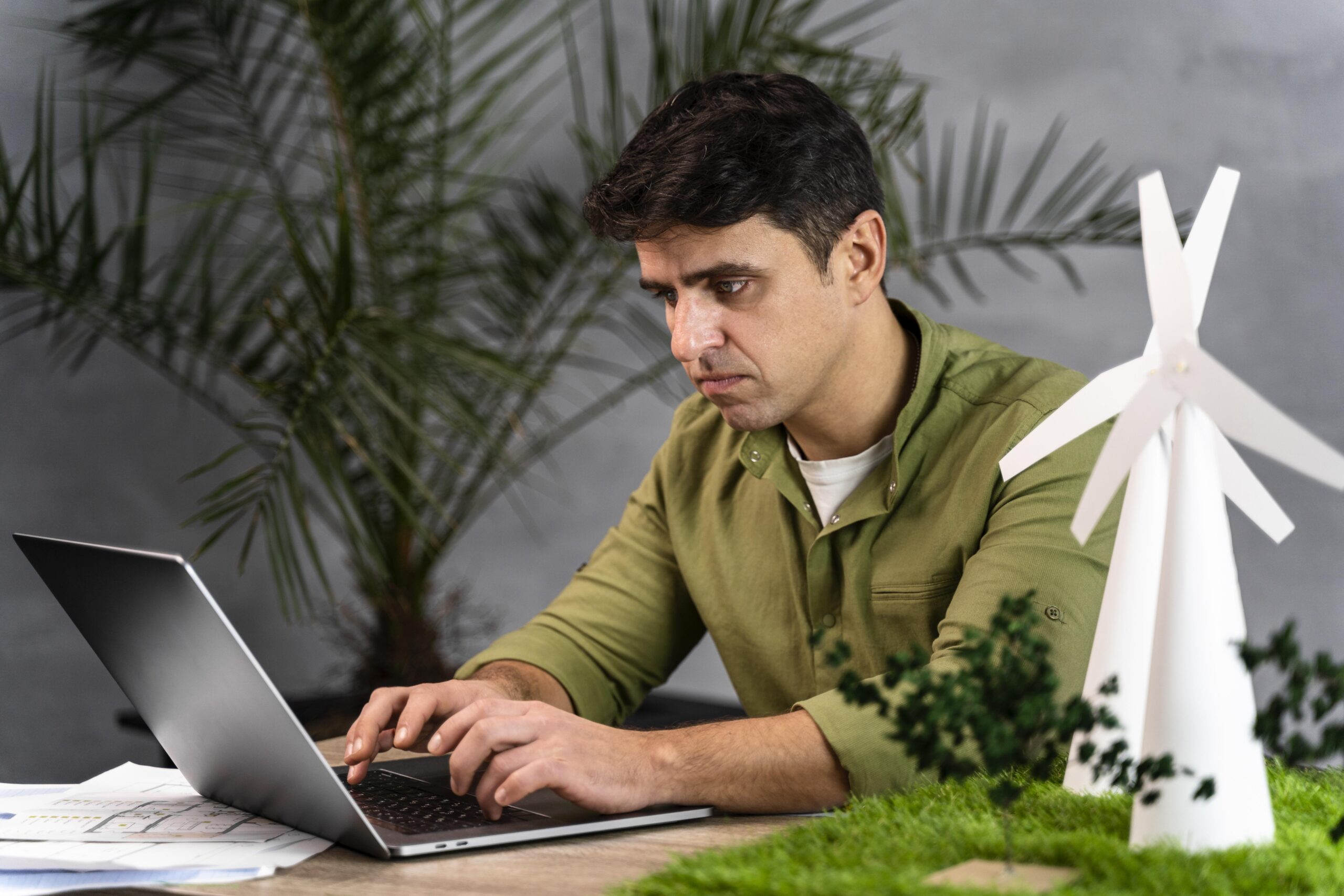 side view man working eco friendly wind power project with laptop scaled